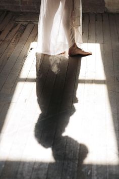 the shadow of a person's feet on a wooden floor