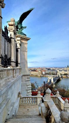 an ornate balcony overlooking the river and city with statues on it's railings