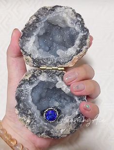 a woman holding two pieces of rock with a blue stone in it's center