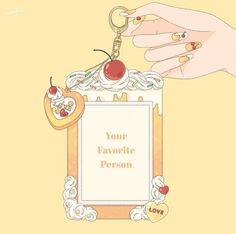 a hand holding a keychain with an image of a cake and cherries on it