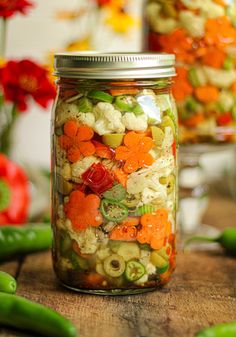 a jar filled with vegetables sitting on top of a wooden table