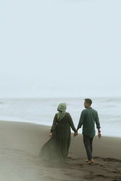 two people walking on the beach holding hands