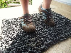 the feet of a person wearing hiking shoes on a black area rug with rocks and gravel