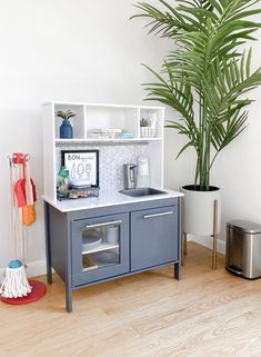 a toy kitchen with a potted plant in the corner