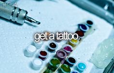 the words get a tattoo are written in front of various colored inks and needles