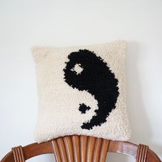 a black and white pillow sitting on top of a wooden chair