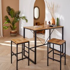 a dining table with two stools and a mirror on the wall in an empty room