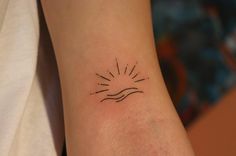 a woman's arm with a small sun tattoo on it