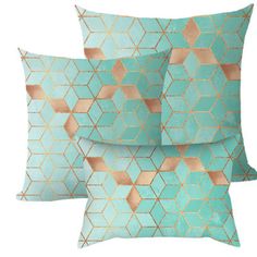 three pillows with gold foil on them, one in aqua and the other in pink