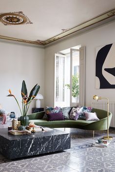 a living room filled with furniture and a painting on the wall next to a window