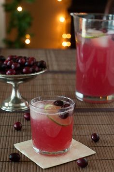 two glasses filled with cranberry juice and garnished with cherries on a table