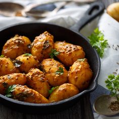 a pan filled with cooked potatoes on top of a wooden table next to some vegetables