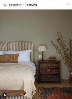 a bed sitting next to a wooden dresser in a bedroom on top of a rug