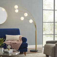 a living room with a blue couch, round mirror and floor lamp in the corner