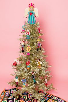 a white christmas tree with ornaments on it and a pink wall in the back ground