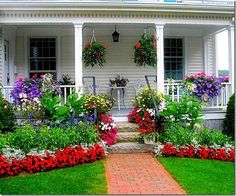 a white house with lots of flowers in the front yard