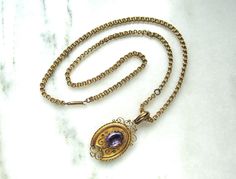 This is a gorgeous antique locket pendant necklace.  The locket has a purple glass stone on the cover that measures 12mm x 9mm.  The back of the pendant is where the locket portion opens.  It holds and old black and white photo of a young man in a suit.  The locket measures 2" long from the top of the bale x 15/16" wide.  The chain is also 14K.  It measures 21 1/2" long.  Total weight of the necklace is 20.8 grams. Victorian Necklace With 17 Jewels In Oval Pendant, Victorian Pendant Locket Necklace For Formal Occasions, Antique Yellow Gold Necklace With Cabochon, Antique Formal Necklace With Oval Pendant, Antique Gemstone Jewelry For Memorial, Antique Oval Pendant Necklace For Formal Occasions, Elegant Round Locket Necklace For Collecting, Formal Victorian Hallmarked Locket Necklace, Antique Oval Pendant Jewelry With 17 Jewels