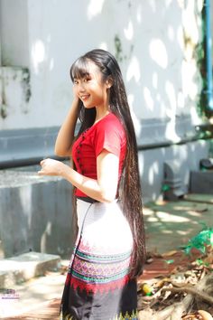 a woman with long hair standing in front of a building and talking on her cell phone