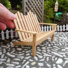 a miniature wooden chair sitting on top of a stone floor next to a white picket fence