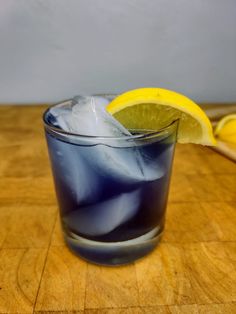 a blue drink with ice and lemon wedges