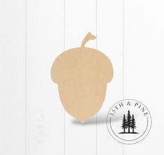 an acorn cutout on a white wood background with the word, stih & pine