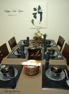 a dining room table set with black and gold place settings