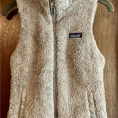 This Patagonia Vest Features A Solid Pattern, Full-Zip Closure, And Sleeveless Design Perfect For Layering. The Gray Color And Fleece Fabric Add A Touch Of Warmth And The Zipper Accents Give It A Stylish Flair. The Brand Is Patagonia And The Size Is Xs, And The Vest Comes With Pockets, Making It Both Functional And Fashionable. This Vest Is New Without Tags, And Measurements Can Be Found In The Pictures. Patagonia Vest, Patagonia Jacket, Patagonia Jackets, Solid Pattern, The Gray, Patagonia Womens, Fleece Fabric, Patagonia, Gray Color