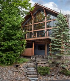 a large house sitting on top of a lush green hillside next to a forest filled with trees