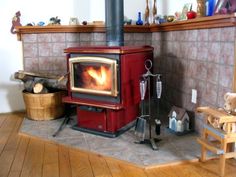 a red stove sitting inside of a kitchen next to a wooden floor and shelves on the wall