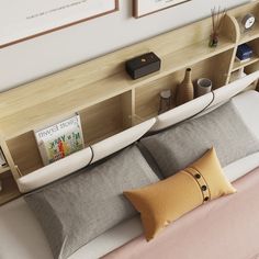 a bed with two pillows and some books on the shelf above it, along with other items