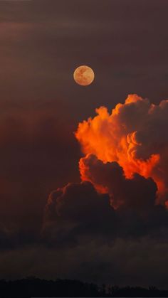 the moon is setting behind some clouds in the sky with orange and red hues