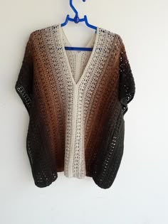 a brown and white knitted sweater hanging on a hanger with a blue hook