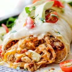 an enchilada on a plate with tomatoes and lettuce