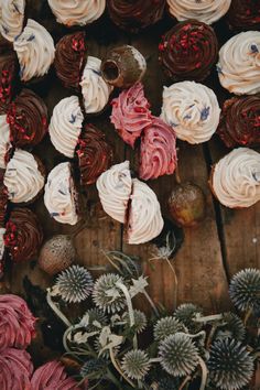 cupcakes with white frosting and red sprinkles on wooden table