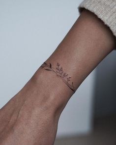 a woman's wrist with a small flower tattoo on the left side of her arm