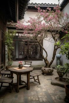 a table and chairs in front of a tree with pink flowers