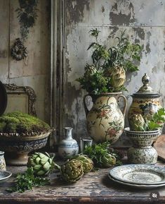 a table topped with vases filled with plants and other decorating items on top of a wooden table