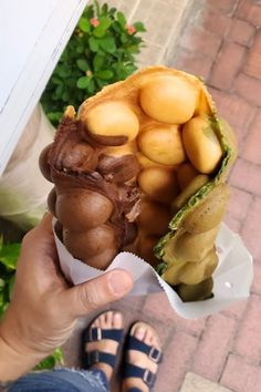 a person holding up a chocolate ice cream cone with fruit in it's wrapper