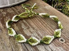 a green and white crocheted bracelet on top of a wooden table