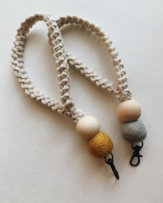 two leashes with different colored balls attached to them on a white surface, one is black and the other is gray