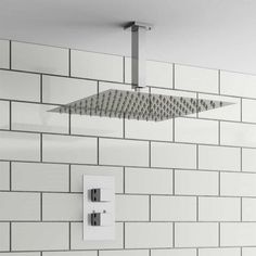 an overhead shower head in a white tiled bathroom