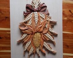 a piece of art made out of corn on the cob with a bow hanging from it