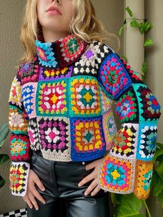 a woman is wearing a colorful crocheted jacket