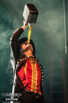 a man in costume holding an object up to his face while performing at a concert