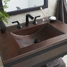 a bathroom sink sitting under a mirror next to a towel rack and a potted plant