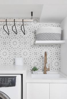 a washer and dryer in a white laundry room with floral wallpaper on the walls