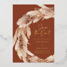 an elegant wedding save the date card with feathers on black and gold foil, in front of a marble background