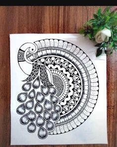 a black and white drawing of a peacock on a piece of paper next to flowers