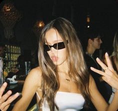 a woman wearing sunglasses making a face while standing in front of other people at a party