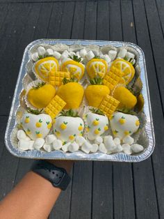 a person holding a tray with lemons and marshmallows on it,